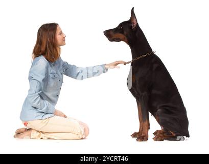 Ragazza seduta in ginocchio davanti a un grande cane nero Foto Stock
