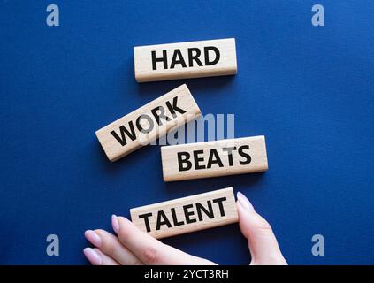 Simbolo del talento. Parole concettuali il duro lavoro batte il talento sui blocchi di legno. Mano d'affari. Splendido sfondo blu intenso. Il lavoro e il duro lavoro battono le t Foto Stock