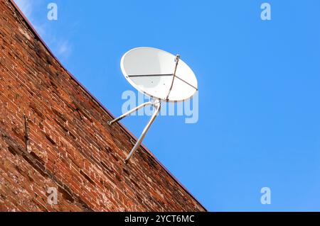 Parabola satellitare montato sul grunge muro di mattoni della casa Foto Stock