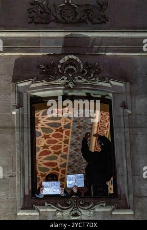 Tbilisi, Georgia. 23 ottobre 2024. I manifestanti tengono i segni da una finestra alta, gettando ombre mentre si trovano in disparte durante la manifestazione a Tbilisi. I messaggi scritti a mano parlano delle lamentele della popolazione. Catturato durante la campagna pre-elettorale del raduno governante georgiano "GD" a Tbilisi, Georgia, mercoledì 23 ottobre 2024. (VX Photo/ Vudi Xhymshiti) crediti: VX Pictures/Alamy Live News Foto Stock