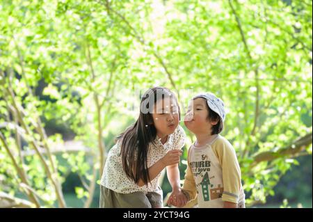 Sorella e fratello che soffiano il dente di leone Foto Stock