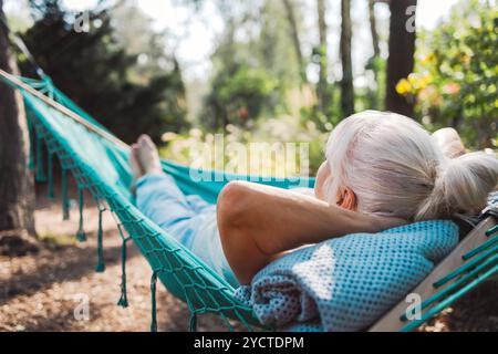 Donna anziana che si rilassa sull'amaca in giardino in una giornata di sole Foto Stock