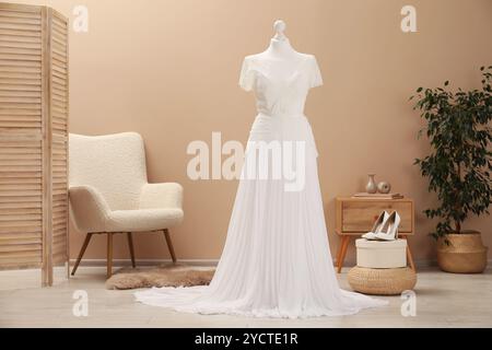 Bellissimo abito da sposa con manichino e scarpe in boutique Foto Stock