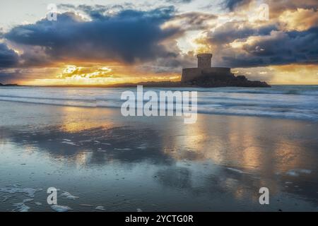 La Torre la Rocco sorge sulla spiaggia sabbiosa al tramonto. Il cielo si riflette nell'acqua. Foto Stock