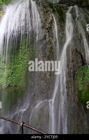 Piccola cascata a cascata contro le rocce di montagna. Foto Stock