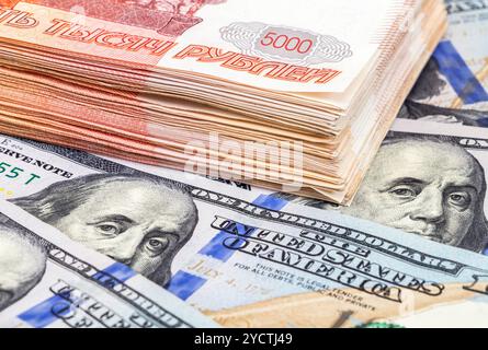 Pila di cinque millesimi banconote di rubli russi e dollari americani close up Foto Stock
