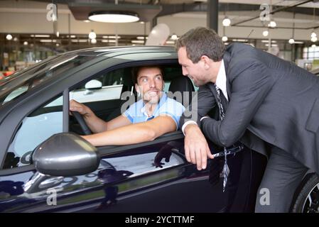 Consulenza in concessionaria auto - venditore e giovane uomo che vende una nuova auto Foto Stock