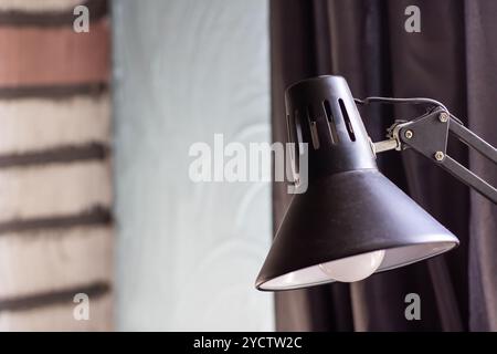 Questa immagine mostra una vista ravvicinata di un'elegante lampada nera con un elegante paralume bianco montato sulla base Foto Stock