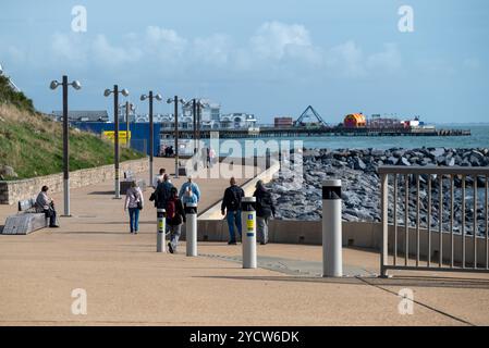 Persone che camminano lungo le nuove difese marittime e la passeggiata a Portsmouth, con South Parade Pier in lontananza. Ottobre 2024. Foto Stock