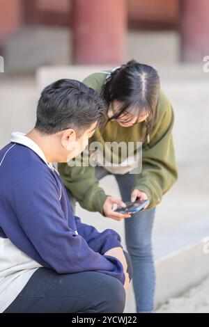 Una coppia coreana sportiva, un uomo di 30 anni e una donna di 20 anni, che indossa tute, trascorrono il loro tempo insieme felicemente in un edificio storico di se Foto Stock