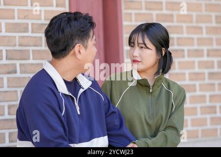 Una coppia coreana sportiva, un uomo di 30 anni e una donna di 20 anni, che indossa tute, trascorrono il loro tempo insieme felicemente in un edificio storico di se Foto Stock