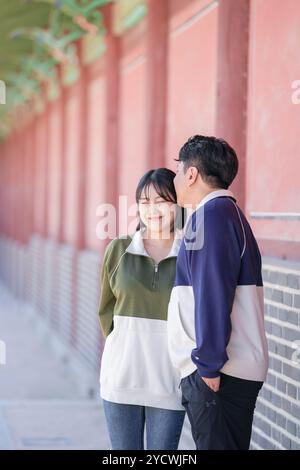 Una coppia coreana sportiva, un uomo di 30 anni e una donna di 20 anni, che indossa tute, trascorrono il loro tempo insieme felicemente in un edificio storico di se Foto Stock