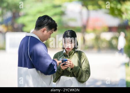 Una coppia coreana sportiva, un uomo di 30 anni e una donna di 20 anni, che indossa tute, trascorrono il loro tempo insieme felicemente in un edificio storico di se Foto Stock