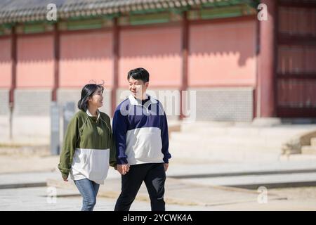 Una coppia coreana sportiva, un uomo di 30 anni e una donna di 20 anni, che indossa tute, trascorrono il loro tempo insieme felicemente in un edificio storico di se Foto Stock