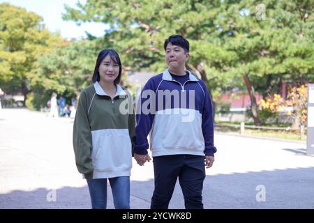 Una coppia coreana sportiva, un uomo di 30 anni e una donna di 20 anni, che indossa tute, trascorrono il loro tempo insieme felicemente in un edificio storico di se Foto Stock