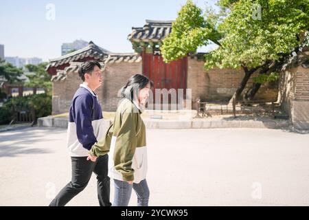 Una coppia coreana sportiva, un uomo di 30 anni e una donna di 20 anni, che indossa tute, trascorrono il loro tempo insieme felicemente in un edificio storico di se Foto Stock