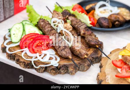 Grigliata di shish kebab spiedini o su spiedini di legno con verdure fresche Foto Stock