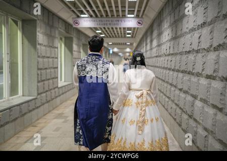 Una coppia di abiti tradizionali coreani camminano lungo un tunnel. L'uomo indossa un gilet blu e la donna indossa un vestito bianco Foto Stock