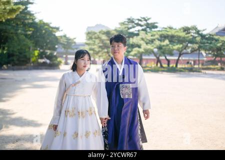 Una coppia coreana, un uomo di 30 anni e una donna di 20 anni, cammina armoniosamente attraverso un edificio storico a Seoul, Corea del Sud, indossando Hanbok. Foto Stock