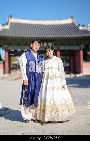 Una coppia coreana, un uomo di 30 anni e una donna di 20 anni, cammina armoniosamente attraverso un edificio storico a Seoul, Corea del Sud, indossando Hanbok. Foto Stock