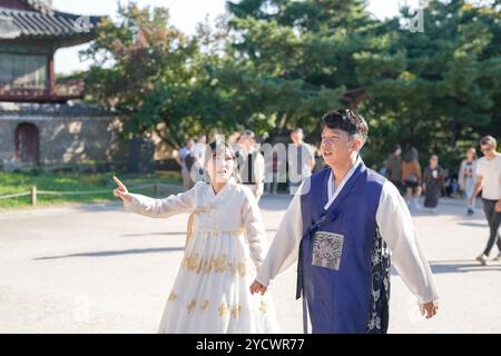 Una coppia coreana, un uomo di 30 anni e una donna di 20 anni, cammina armoniosamente attraverso un edificio storico a Seoul, Corea del Sud, indossando Hanbok. Foto Stock