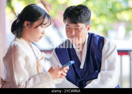 Una coppia coreana, un uomo di 30 anni e una donna di 20 anni, indossa felicemente Hanbok e siede in un edificio storico a Seoul, Corea del Sud. Foto Stock