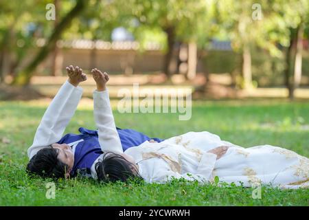 Una coppia coreana di 30 anni e una donna di 20 anni guardano il cielo in un parco verde circondato da alberi mentre indossa Hanbok a Seoul, Sud Foto Stock