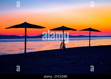 Spiaggia e ombrelloni sulla colorata vista tramonto Foto Stock