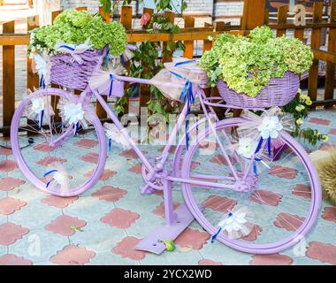 Vintage pink bicycle decorated with green flowers and white bows, artistic retro object Foto Stock