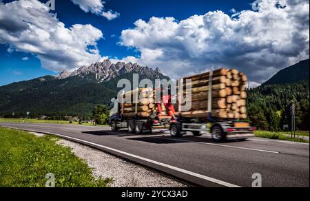 Legname camion precipita l'autostrada sullo sfondo delle Alpi. Carrello Car in motion blur. Foto Stock