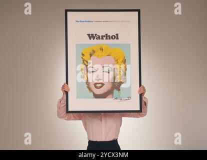 Un membro dello staff della galleria che tiene in mano un poster firmato della Tate Gallery di Andy Warhol, Marilyn Monroe, 1971 anni, durante una chiamata fotografica presso la nuova galleria Shapero Modern Muse di Londra, per la loro prima mostra, The Modern Muse, con opere famose di Andy Warhol, David Hockney, Picasso, Grayson Perry e Banksy su tela raffigurante Kate Moss, con i capelli e il caratteristico punto di bellezza di Marilyn Monroe. Data foto: Giovedì 24 ottobre 2024. Foto Stock