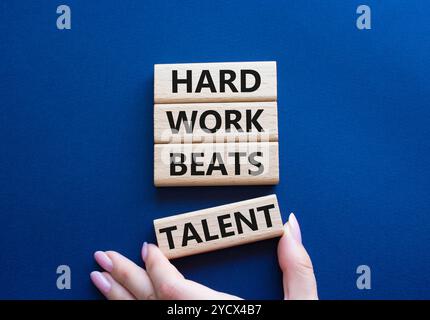 Simbolo del talento. Parole concettuali il duro lavoro batte il talento sui blocchi di legno. Mano d'affari. Splendido sfondo blu intenso. Il lavoro e il duro lavoro battono le t Foto Stock