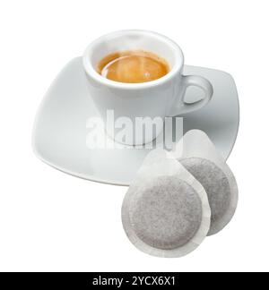 Una tazza di caffè fumante si trova su un piattino bianco con due cialde di caffè appoggiate in primo piano Foto Stock