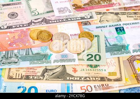 Monete diverse che giacciono su banconote, euro, dollari e rubli in primo piano. Background di denaro Foto Stock