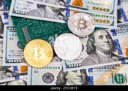 Monete di criptovaluta che si trovano sopra dollari americani e circuiti elettronici. Concetto di business Foto Stock