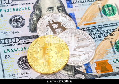 Monete di criptovaluta che giacciono oltre cento banconote in dollari americani Foto Stock