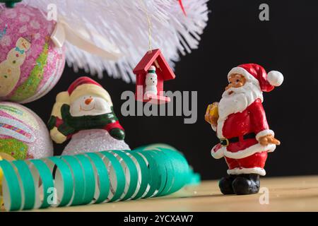 Una piccola statuetta di Babbo Natale in una tuta rossa e bianca che regge un sacco verde, su uno sfondo sfocato. Questo ornamento natalizio cattura l'spi Foto Stock