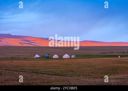 Yurte e montagne intorno al lago Song Kul sotto la luce del tramonto, Kirghizistan Foto Stock