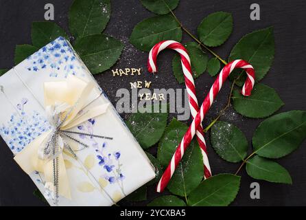 Iscrizione del nuovo anno su una lavagna nera con regalo e caramelle rosse Foto Stock