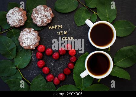 Iscrizione del nuovo anno su un tabellone nero con cupcake Foto Stock