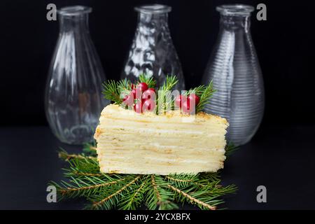 Fetta di torta decorata con alberi e frutti di bosco su sfondo nero con vasi Foto Stock