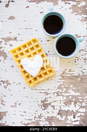 Waffle belgi e due tazze di caffè su un vecchio tavolo di legno. Foto Stock