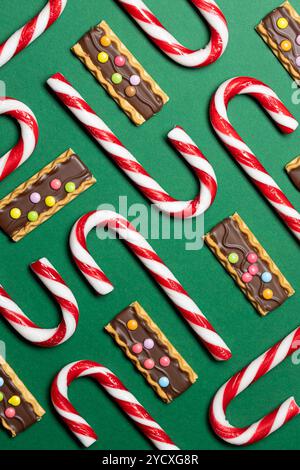Vista dall'alto delle caramelle natalizie, tra cui canne di caramelle rosse e bianche e biscotti ricoperti di cioccolato conditi con caramelle colorate, arrangiate artisticamente Foto Stock