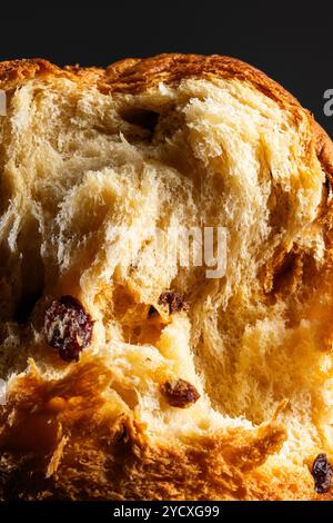 Vista ravvicinata che mostra la consistenza soffice e la crosta dorata di un tradizionale panettone, costellato di succose uvetta, tipici dei dolci natalizi Foto Stock