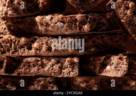 Un'immagine ravvicinata che mostra strati di torrone denso e ricco di cioccolato e riso soffiato, con una texture dettagliata che mette in risalto la miscela cremosa e croccante. Foto Stock