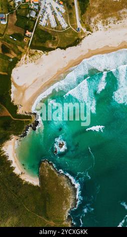Incredibile colpo di droni che si affaccia sulla costa frastagliata e sulle acque turchesi della Galizia, con spiagge sabbiose e un parcheggio affollato Foto Stock
