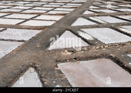 Vista aerea delle saline che mostrano motivi geometrici pieni di acqua di mare in evaporazione, utilizzata nella produzione tradizionale di sale Foto Stock