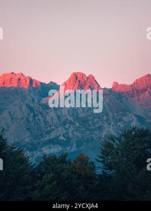 L'alba si interrompe sull'aspro terreno montano dei Picos de Europa, evidenziato da un caldo bagliore rosa che illumina le vette. Foto Stock