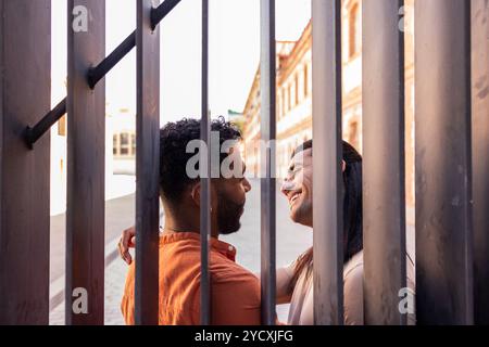 Una coppia gay amorevole, che rappresenta il patrimonio latino americano e afroamericano, condivide un momento di gioia tra i bar di metal urbani, evidenziando Foto Stock