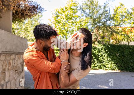 Un abbraccio amorevole tra una coppia gay multietnica in un ambiente urbano, catturando un momento di gioia e intimità, illustrando la diversità all'interno della L Foto Stock